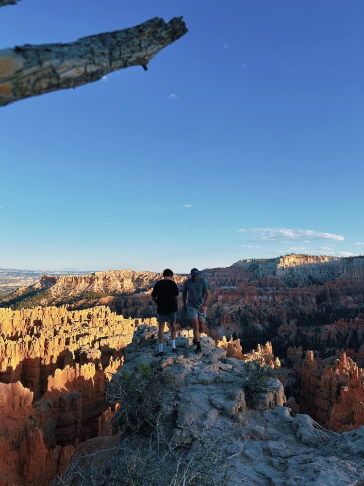 Two of the crew standing on an outcrop above the canyon at golden hour.